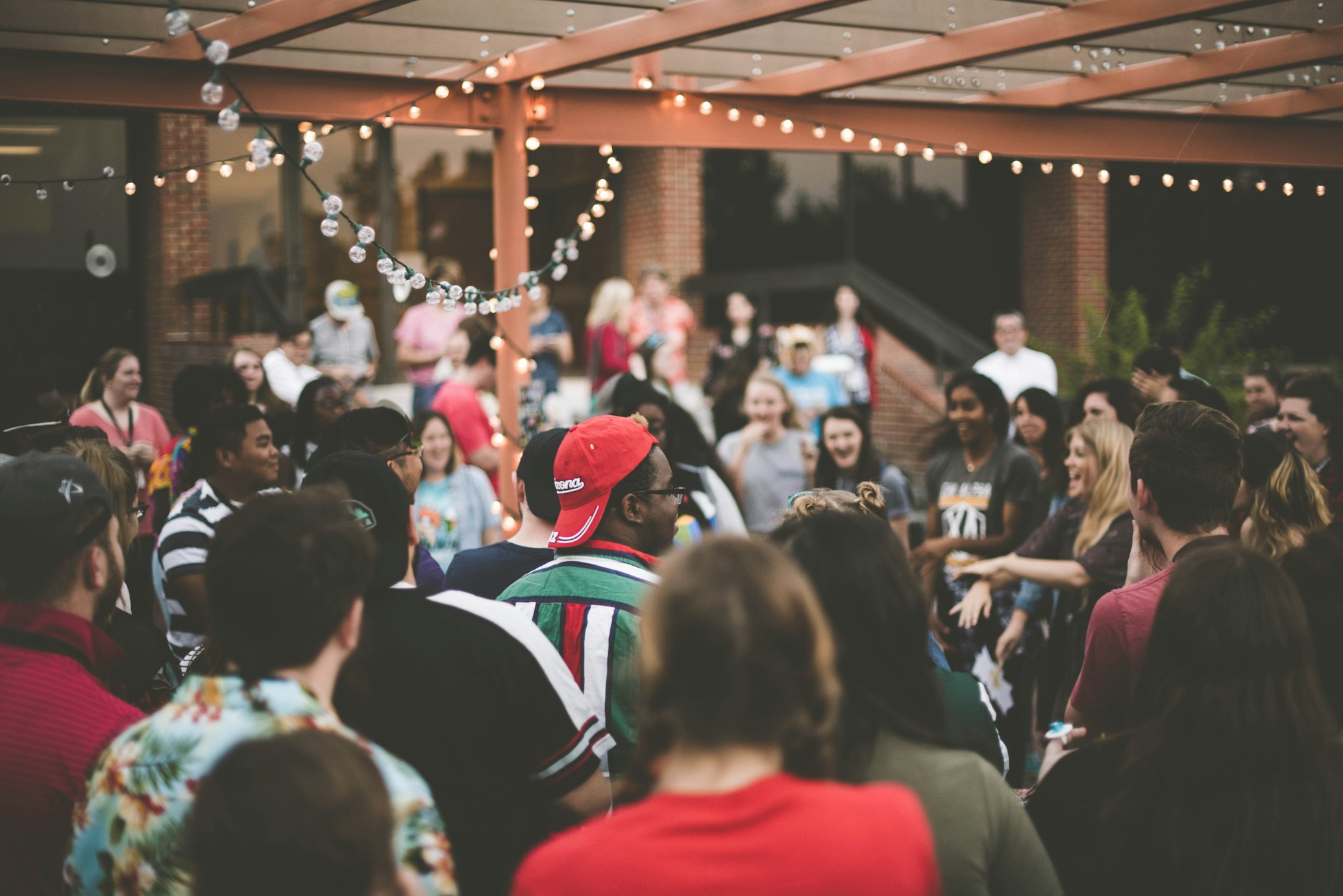 A crowd under warm string lights at an evening celebration
