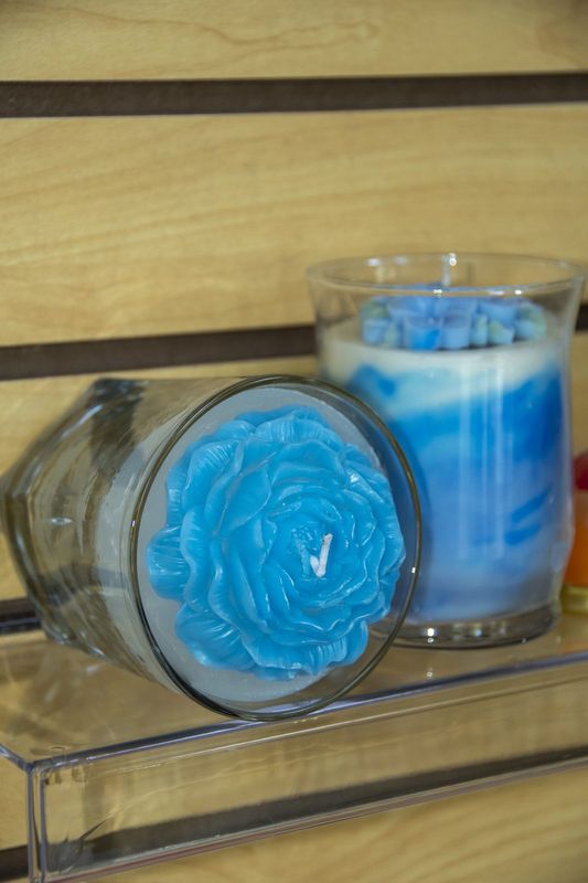 A blue rose candle set in a clear glass jar
