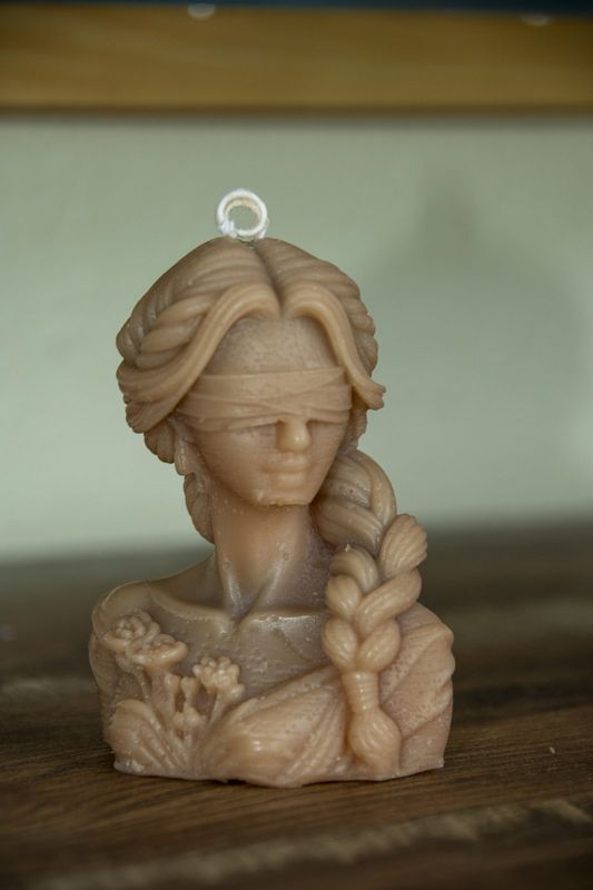 A sculpted bust candle with a long braid